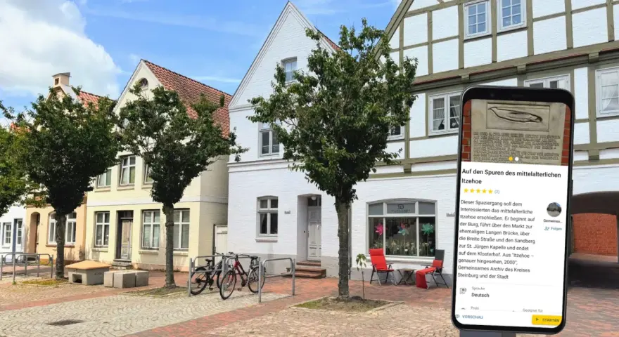 Blick auf die mittelalterliche Itzehoe Altstadt mit Fachwerkhäusern und einem Smartphone, das Informationen über die Stadt anzeigt.