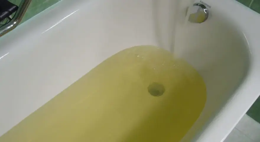 Wanna z żółtą wodą, z kranu leje się woda.