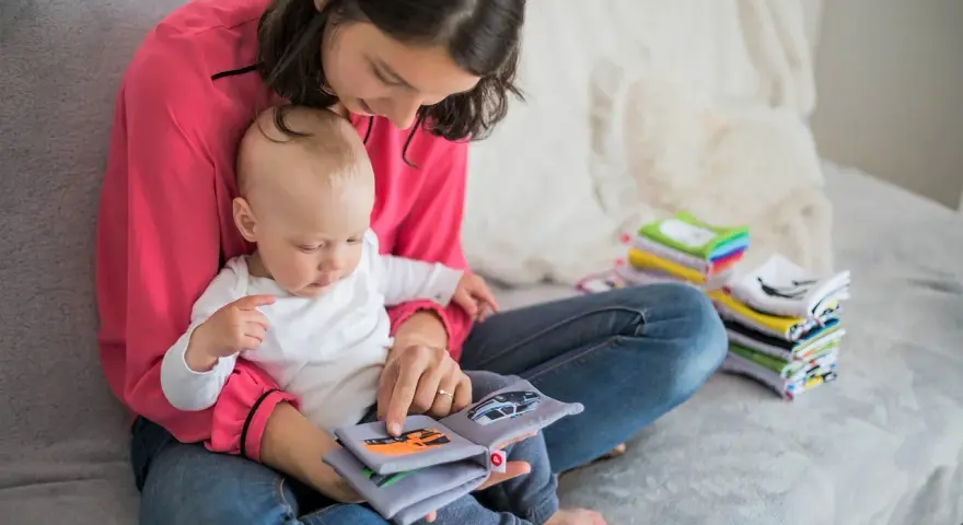 Mama czyta dziecku książeczkę o samochodach. Wycofane dziecko, przyczyny jego nieśmiałości mogą być różne, ale wspólne czytanie buduje więź.
