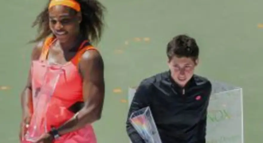 Serena Williams, con su impresionante altura, celebra con un trofeo. A su lado, otra tenista recibe su premio.