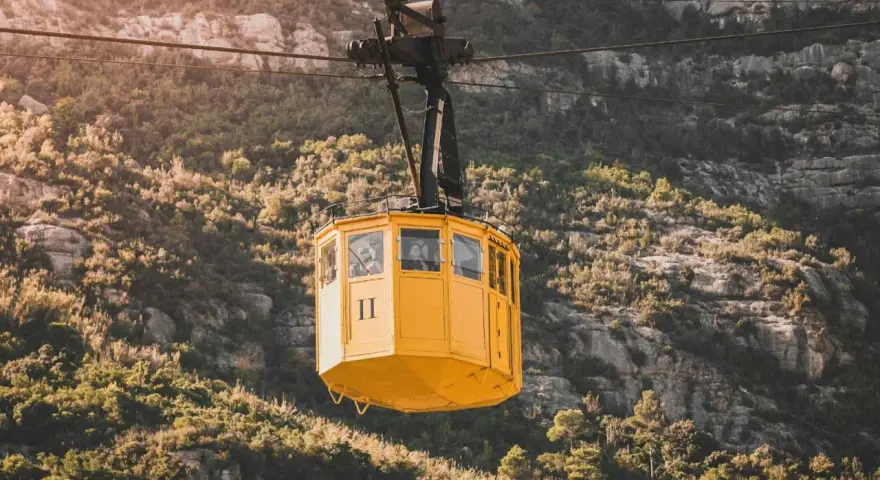 A yellow cable car ascends the rugged slopes of Montserrat.