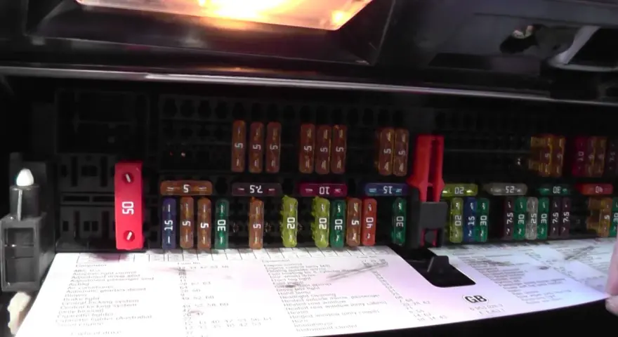 Panel z bezpiecznikami BMW E46, z czerwonym bezpiecznikiem 50A i innymi o różnej wartości.