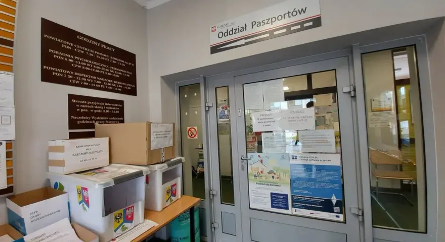 Oddział Paszportów w Zielonej Górze. W holu stoją pudła i pojemniki, a na drzwiach wiszą ogłoszenia.