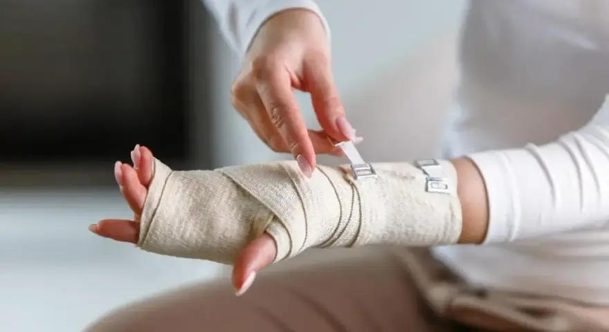 Dłoń owinięta bandażem, zapięcie na rzepy. Prezentacja bandażowania po urazie.