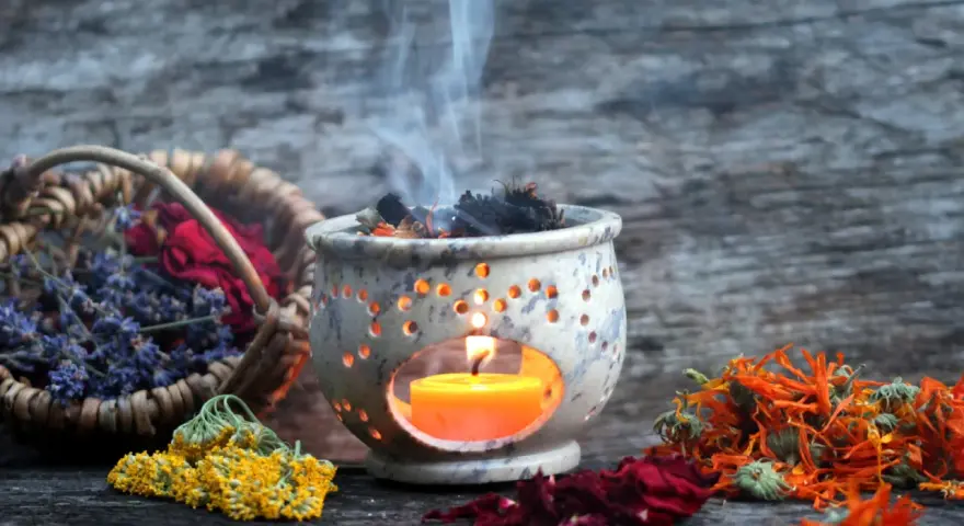 Aromas de lavanda, rosas y caléndula se elevan con el humo de un quemador de incienso, creando un ambiente de limpieza de energías.