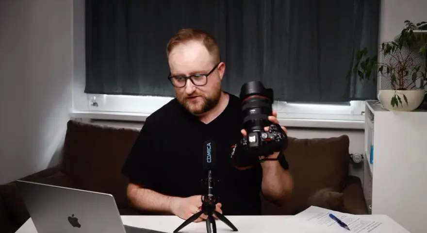 Mężczyzna prezentuje aparat fotograficzny, omawiając elementy kursu fotografii dla początkujących.