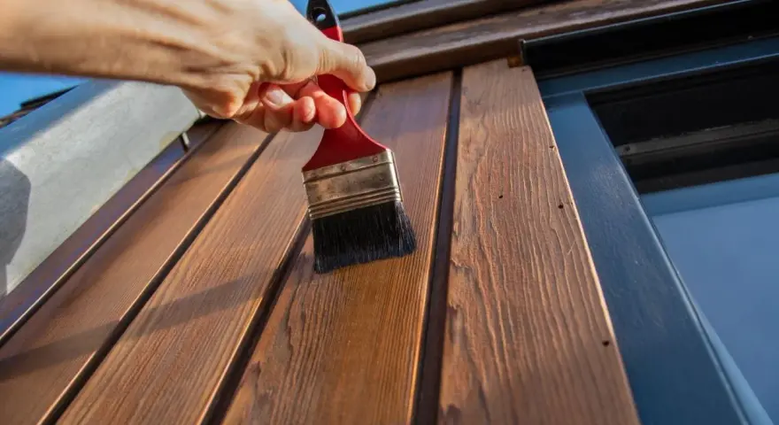 Application d'une couche protectrice sur des lattes de bois avec une peinture à l'huile sur bois technique.