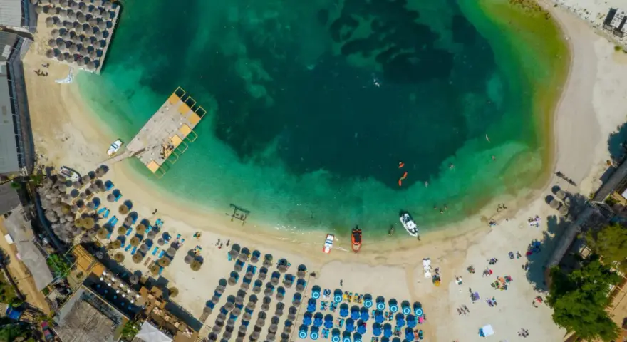 Rajska plaża w Albanii, idealne miejsce na wakacje. Turkusowa woda, złoty piasek i mnóstwo leżaków pod parasolami.