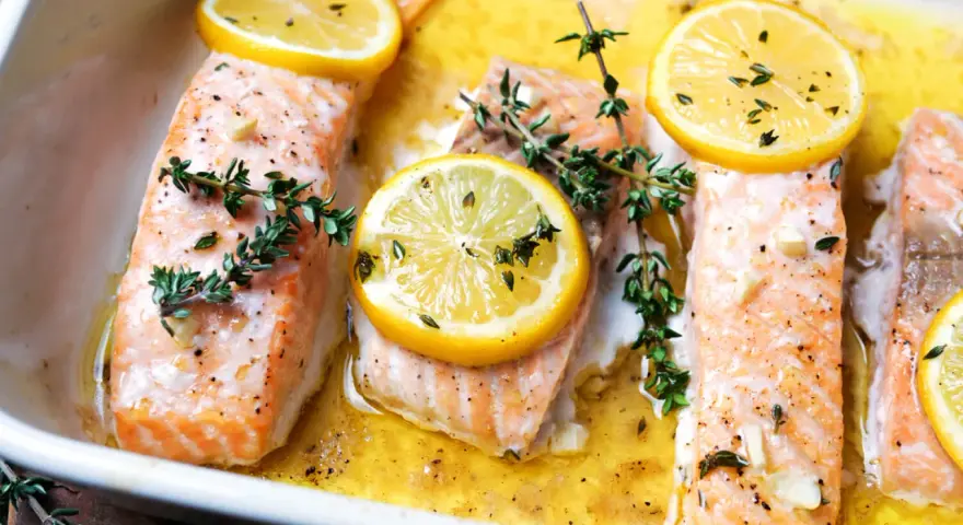 Saftiger Lachs im Ofen, garniert mit Zitronenscheiben und frischem Thymian, bereit zum Genießen.