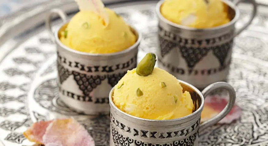 Gelbes Eis mit Pistazien in silbernen Bechern. Die süße Glucose-Verwendung sorgt für die cremige Konsistenz.