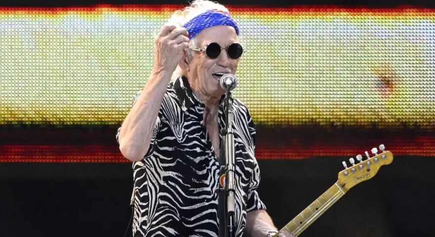 Keith Richards heute, mit blauem Bandana und Sonnenbrille, spielt Gitarre auf der Bühne.