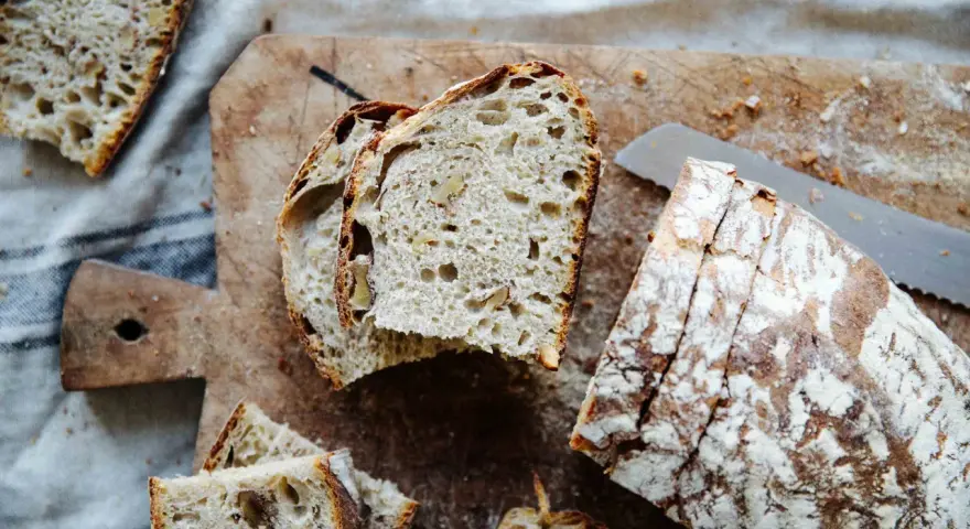 Frisches Brot mit Nüssen, perfekt **mit Dampf gebacken**, liegt auf einem Holzbrett.