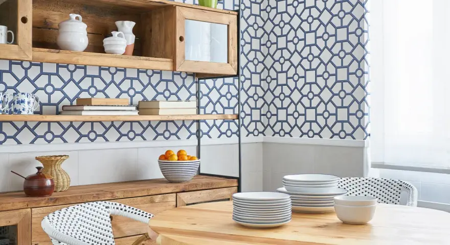 Cocinas con papel pintado azul y blanco, estanterías de madera, vajilla y una mesa de comedor.