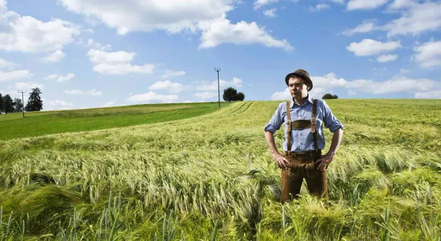 Un homme en culotte de peau et chapeau se tient dans un champ d'orge. Son nom, Hoffmann, pourrait avoir une origine juive, évoquant une histoire ancestrale.