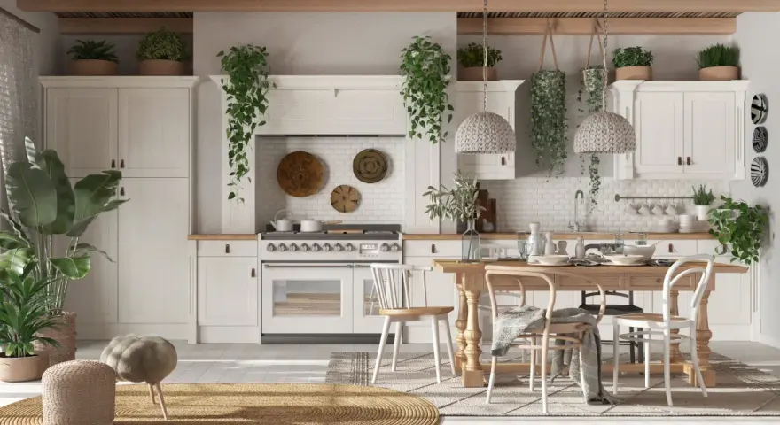 Cucina luminosa con mobili chiari, tante piante e un tavolo in legno. Un'atmosfera country chic rilassante.