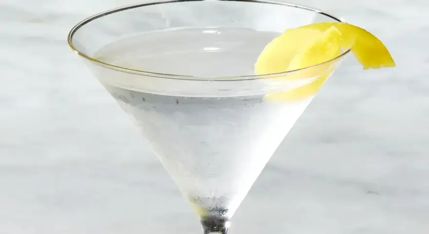 Chłodny martini z ginem, ozdobiony skórką cytryny, czeka na degustację.