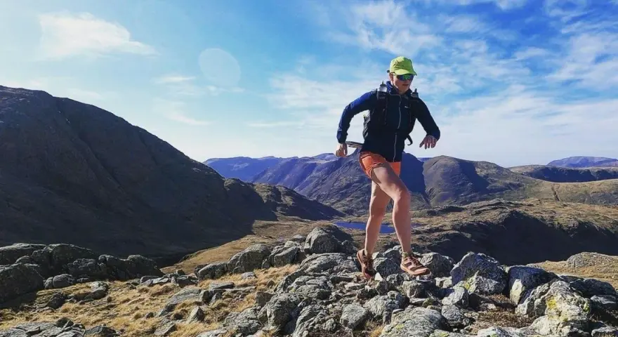 Atleta corre su sentiero roccioso in montagna. Il fast hiking significato è correre in montagna con attrezzatura leggera.