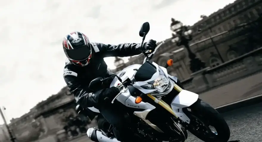 Motocyklista na białym Suzuki GSR 750 pokonuje zakręt. Nawet z potencjalnymi wadami, jazda nim to czysta przyjemność.