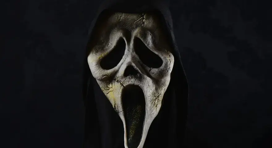 Maschera iconica di Ghostface, simbolo di horror paurosi, con cappuccio nero e sfondo scuro.