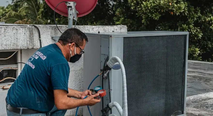 Technik sprawdza czujnik ciśnienia klimatyzacji na dachu, używając manometru.