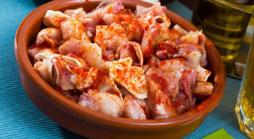 Oreja a la gallega, trozos de oreja de cerdo con pimentón en una cazuela de barro, listos para disfrutar.