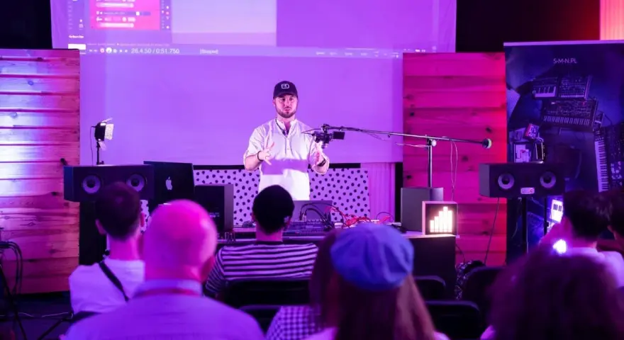 Prezentacja muzyczna z efektami, jak spring reverb. Mężczyzna mówi do mikrofonu, na ekranie widać program do produkcji muzyki.