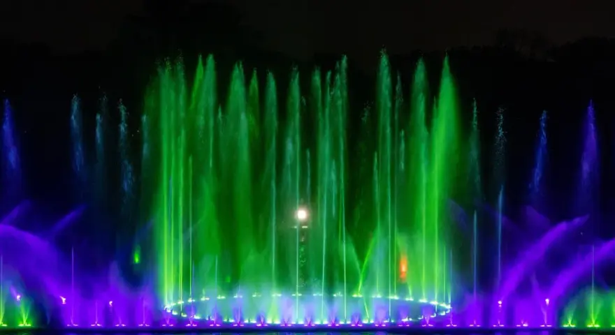 Spektakularna fontanna multimedialna we Wrocławiu nocą, tańczące strumienie wody w zielonych i fioletowych barwach tworzą magiczny pokaz.