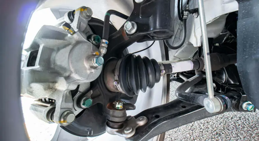Parti di un'auto: pinza freno, giunto sferico e semiasse con soffietto integro, pronto per la sostituzione in caso di rottura semiasse.