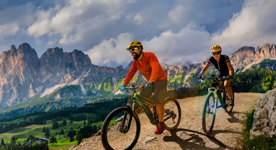 Due ciclisti si godono uno sport di montagna su sentieri sterrati con maestose vette sullo sfondo.