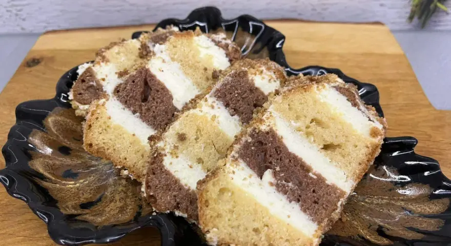 Pyszne ciasto metrowiec, stary przepis, z kremem i czekoladowymi warstwami, na czarnym talerzu.