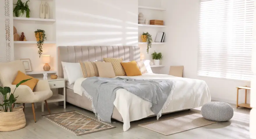 Dormitorio de matrimonio con las ultimas tendencias en decoracion: cama confortable, sillón acogedor, estanterías con plantas y luz natural.