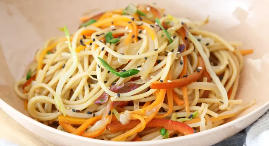 Chow mein en un tazón con verduras y semillas de sésamo.