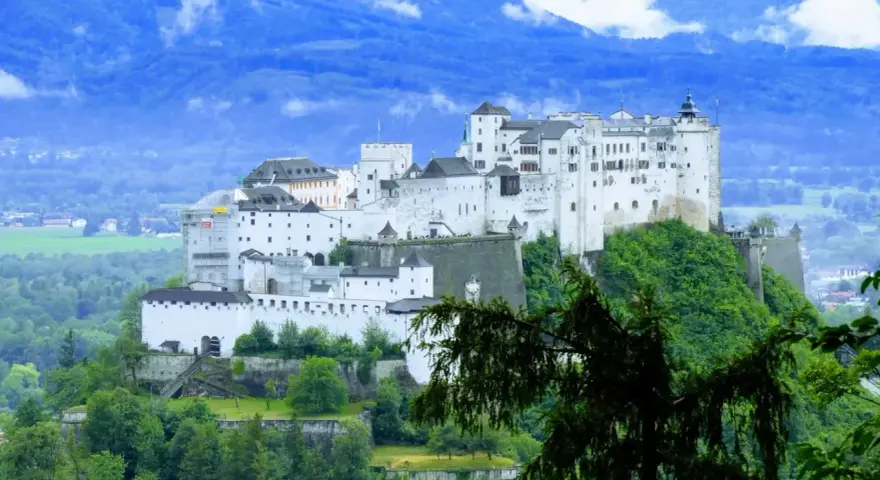 Majestatyczna twierdza Hohensalzburg, jedna z głównych salzburg atrakcje, góruje nad zielonymi wzgórzami.