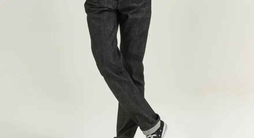 Uomo con jeans scuri e sneakers, che incarnano il comfort fit significato di libertà di movimento e stile casual.
