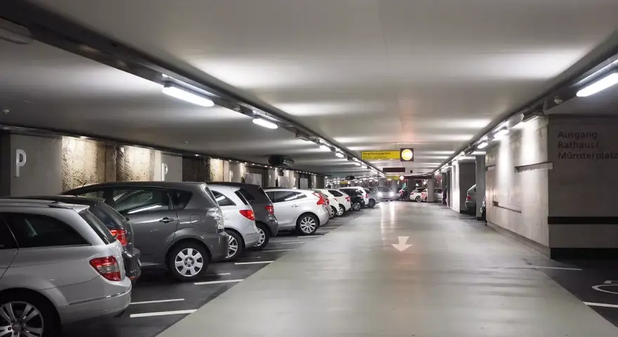 Podziemny parking z rzędami samochodów. Dostępny jest wynajem miejsca parkingowego.