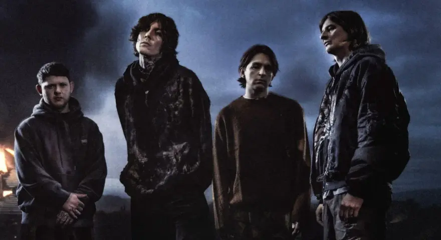 Członkowie Bring Me The Horizon stoją w mrocznej scenerii, z ognistymi płomieniami w tle.
