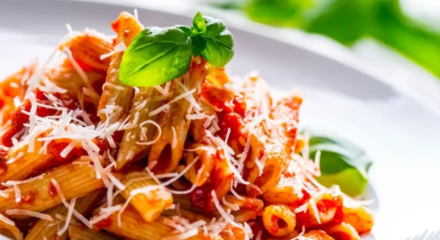 Penne al pomodoro con basilico fresco e parmigiano grattugiato, un classico tra i sughi per pasta.