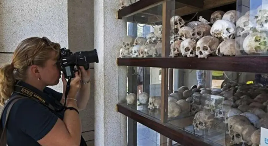 Kobieta fotografuje ludzkie czaszki na wystawie upamiętniającej pola śmierci w Kambodży.