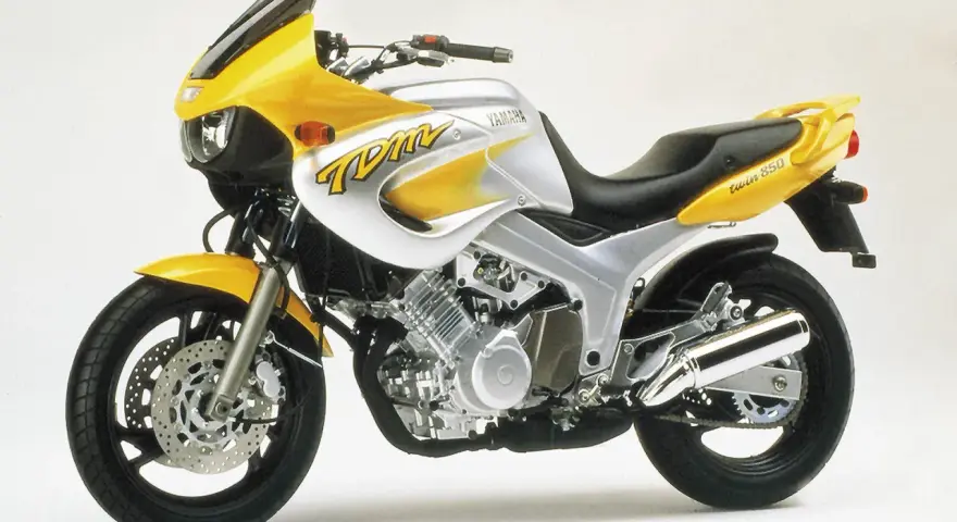 Żółto-srebrny motocykl Yamaha TDM 850 z charakterystycznym napisem "TDM" na baku. Gotowy na przygodę!