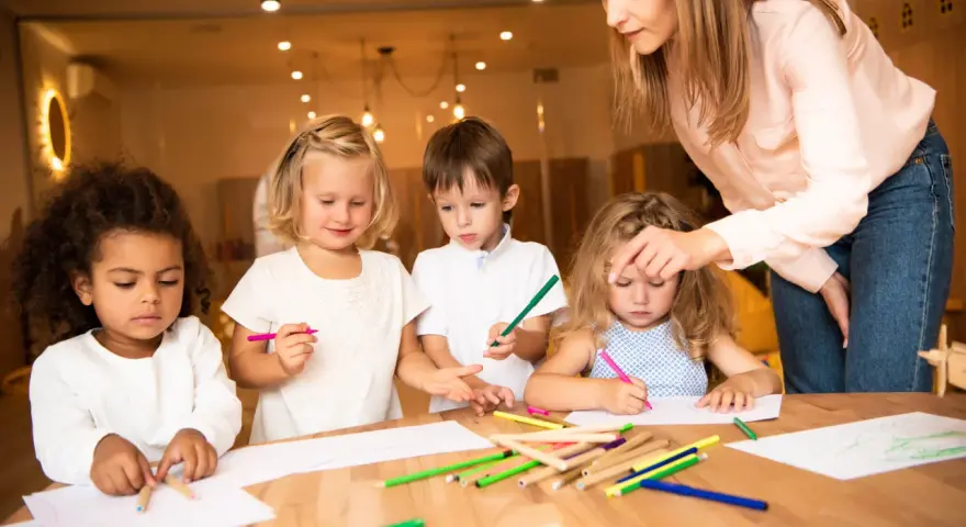 Nauczycielka wspiera dzieci w kreatywnym rysowaniu, promując edukację alternatywną.