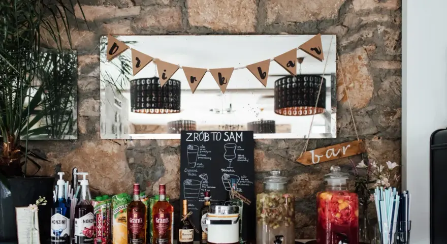 Stół z butelkami alkoholu, sokami i dzbankami z owocami, gotowy na drinki na wesele.