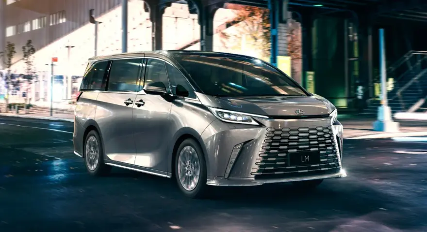 Srebrny van Lexus LM 350h na nocnej ulicy z rozmytym tłem.