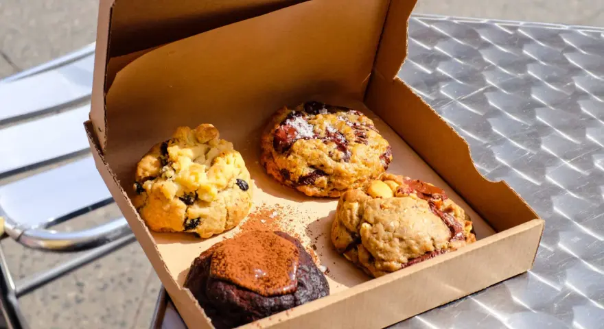 Vier köstliche, hausgemachte Cookies in einer Pappschachtel – die besten Cookies Berlins, bereit zum Genießen.