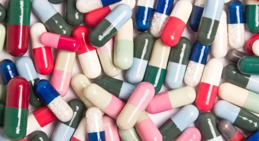 Kolorowe kapsułki leków, które mogą wywołać pieczenie pochwy po antybiotyku.