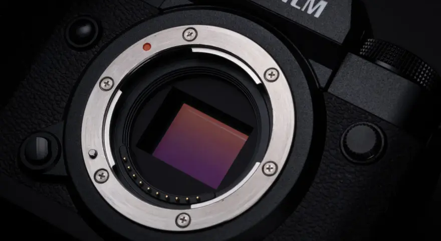 Zbliżenie na matrycę aparatu Fujifilm xh2s, lśniący metalowy pierścień mocowania obiektywu i czerwona kropka sygnalizująca montaż.