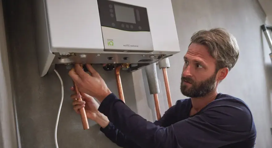 Installazione di una caldaia. Si sente il rumore dell'acqua che scorre mentre un tecnico collega i tubi di rame.