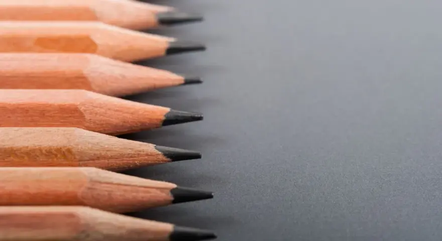 Filas de lápices de madera con puntas afiladas, listos para dibujar. La dureza de los lápices varía, ofreciendo distintas tonalidades.