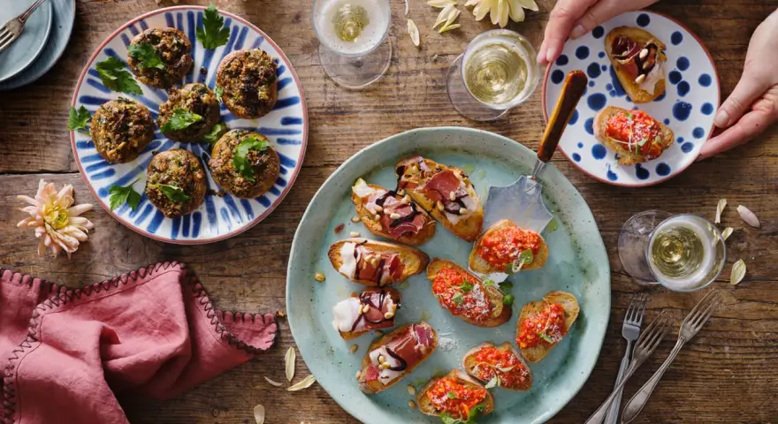 En härlig uppdukning med olika tapas recept. Små bruschettas med tomat, prosciutto och ost, samt fyllda champinjoner. Perfekt för en festlig stund!