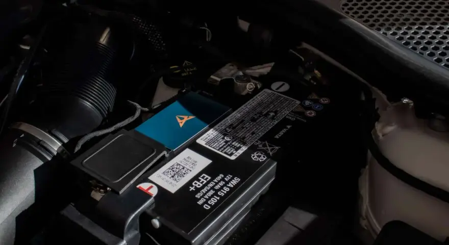 Akumulator w Audi Q7 znajduje się pod maską, obok filtra powietrza. Widoczny jest też niebieski gadżet z logo Cupra.