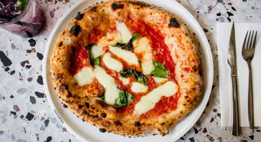 Pizza Margherita: darauf sind Tomatensauce, Mozzarella und frische Basilikumblätter.